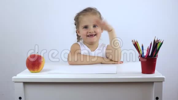一个快乐的小女孩坐在桌边拉着她的手笑了视频的预览图