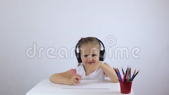 戴着耳机的小女孩坐在书桌前聊天视频的预览图
