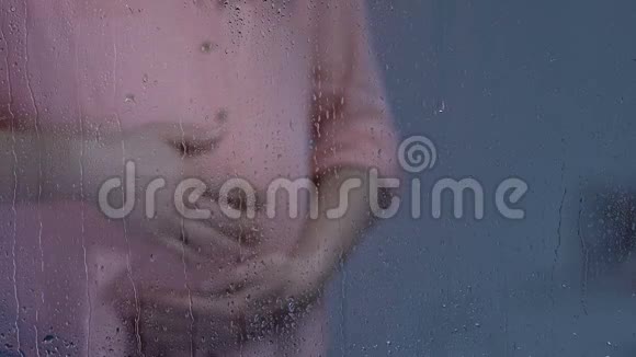 孤独的孕妇在雨窗后抚摸着大肚子心情沮丧视频的预览图