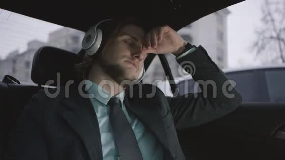 穿着开心果衬衫和灰色西装的棕色头发的人坐在车上系安全带听音乐视频的预览图