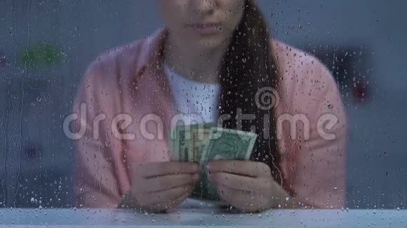 可怜的中年女性在雨窗里数着美元现金视频的预览图