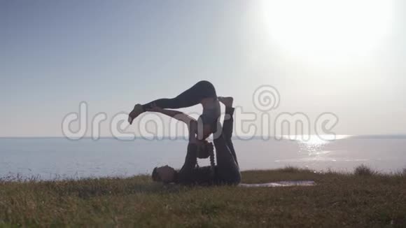 健康的生活方式瑜伽双人正在草地上做运动享受大自然海洋的清新空气视频的预览图