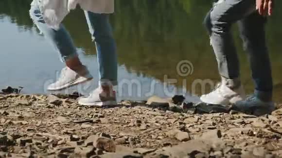 两个徒步旅行者沿着湖的岩石海岸散步视频的预览图