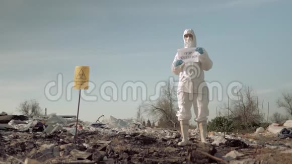 环保运动戴着面具和服装的女孩在垃圾站举着带有防止污染标语的海报视频的预览图