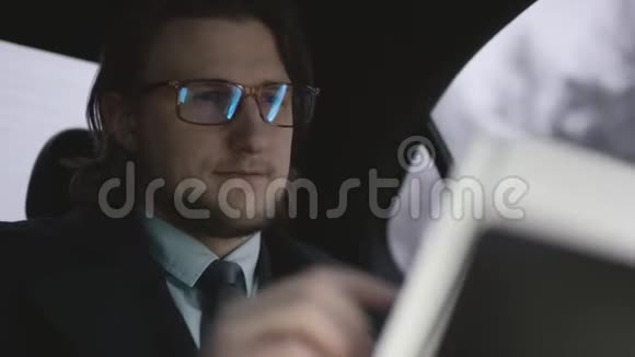 英俊的男子棕色头发穿着开心果衬衫灰色外套坐在车里戴着眼镜看文件视频的预览图