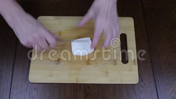 用手在沙拉的木切割板上切希腊菲塔基奶酪食物视频的预览图