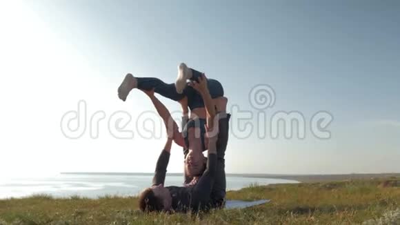 在天空的背景下运动的女人在草地上平衡她的男伴的手视频的预览图