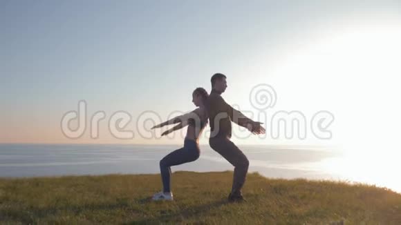 在日落时分运动情侣背靠背同时蜷缩在山上与美丽的风景相映成趣视频的预览图