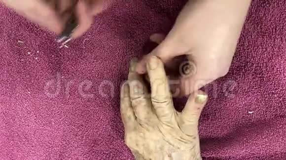 年轻照顾者用剪刀剪老年妇女的指甲癣或无骨癣常见于老年人视频的预览图