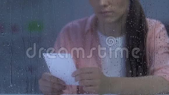 女青年在雨窗旁拿着家庭照很苦恼离婚视频的预览图