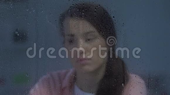 坐在雨窗后的不开心沮丧孤独的女士正在遭受离婚视频的预览图