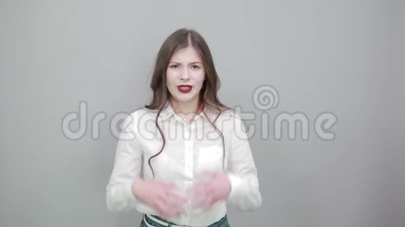 失望的年轻女子穿着白色衬衫双手摊在灰色的墙上视频的预览图