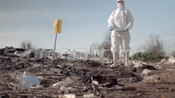 生态灾害妇女穿着防护服戴着口罩在垃圾填埋场附近张贴有防止污染标语的海报视频的预览图
