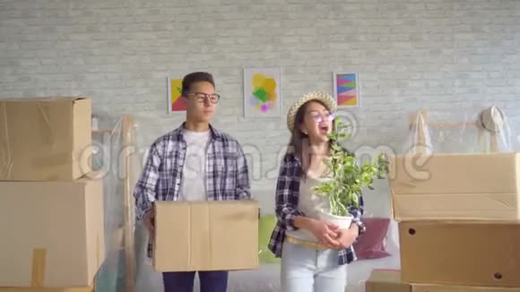 积极的亚洲年轻夫妇手里拿着箱子搬进了新公寓视频的预览图