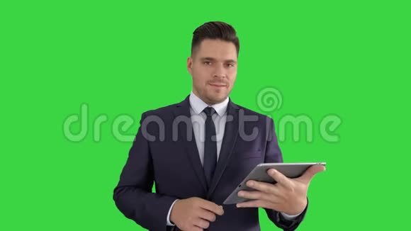 英俊的男人在平板电脑上翻页在绿色屏幕上微笑着对着相机键视频的预览图
