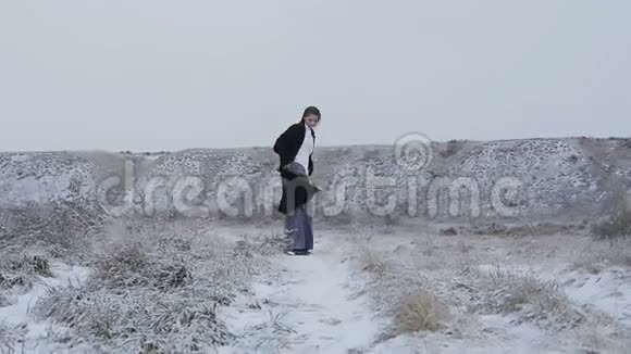一个穿着严格的西装穿着黑色外套的女孩走在白雪覆盖的山上视频的预览图