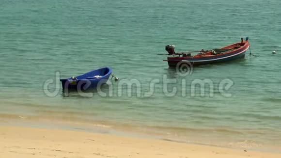 一艘红船和一艘蓝船停泊在海滩上视频的预览图