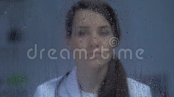 手术后疲惫的女医生站在雨窗附近病人死亡视频的预览图