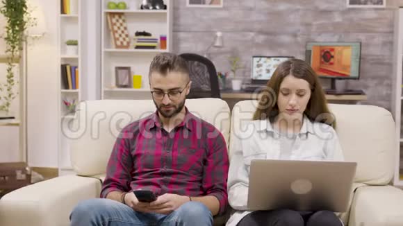 一对漂亮的夫妇坐在沙发上做网上购物视频的预览图