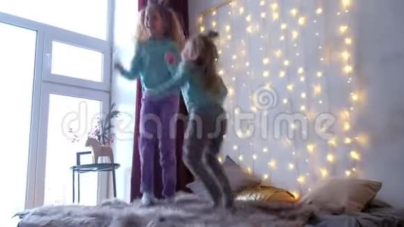 两个女孩姐妹在家里跳着床在的内部有花环视频的预览图