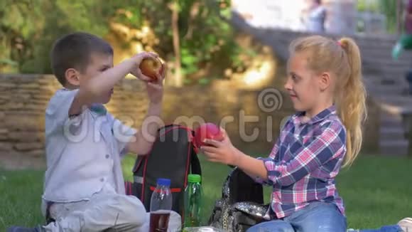 孩子的问题是没有牛奶牙齿的小男孩咬苹果然后心烦意乱把水果放在背包里坐着视频的预览图