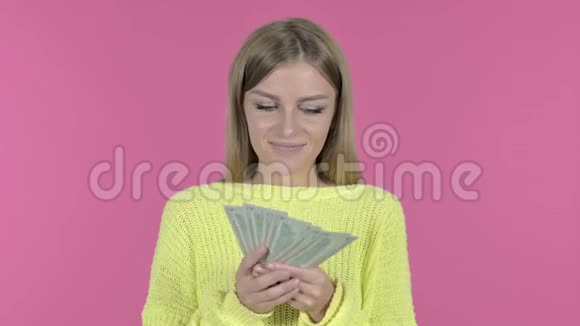 带着钱和笑容的快乐少女粉色背景视频的预览图