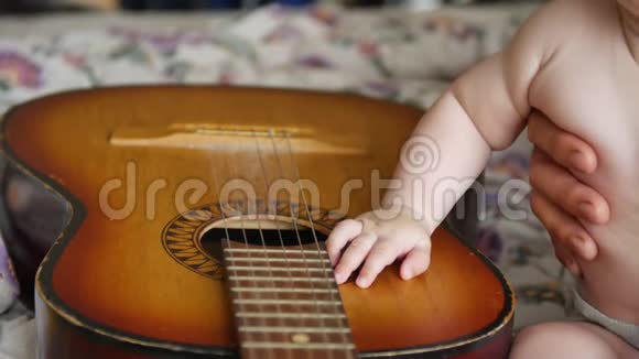 小男孩坐在一把老式吉他旁边触摸琴弦黑白猫坐在附近视频的预览图