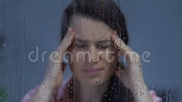 女人头痛得厉害按摩太阳穴望着雨窗视频的预览图