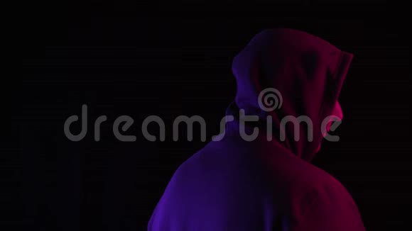 穿着帽衫戴太阳镜的男人在黑暗中看着摄像机视频的预览图