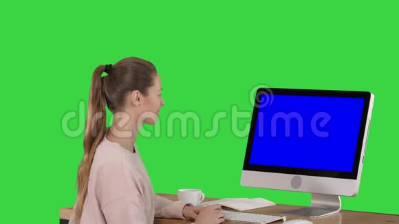 女孩坐在电脑显示器前看着绿色的蓝色屏幕模型显示视频的预览图
