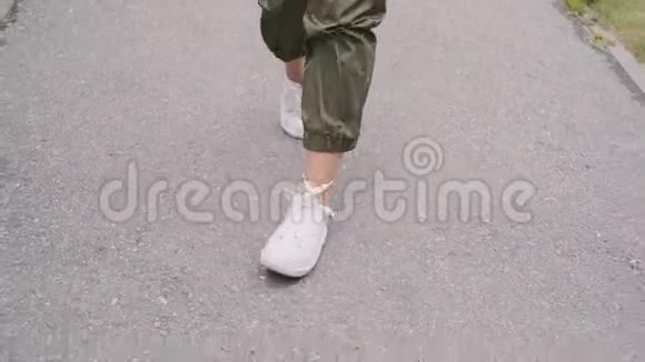 穿着白色运动鞋的时髦女孩正在公园里跳跃用便携式扬声器听音乐视频的预览图