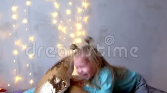 两个女孩姐妹在圣诞节的室内用花环在床上嬉戏视频的预览图