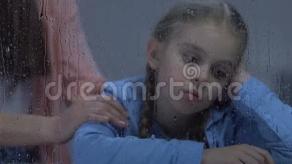 妈妈轻轻抚摸着坐在雨窗旁的小女儿扶着她视频的预览图