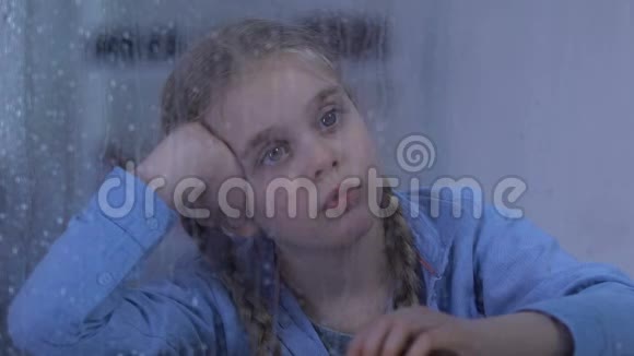 孤儿女孩看着雨寄养家庭站在后面希望有新的生活视频的预览图