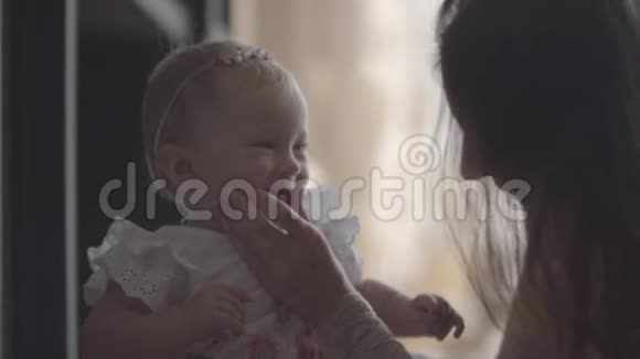 一个年轻的女人在家里和她美丽的微笑女婴玩耍的特写镜头幸福家庭一个孩子的概念视频的预览图