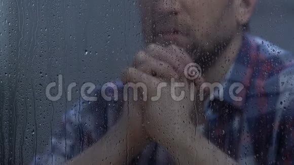 中年男性在雨窗后祈祷上帝希望更好信仰视频的预览图