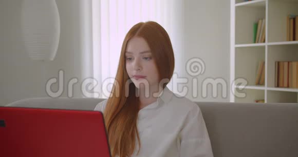 年轻漂亮红头发的女学生用笔记本电脑和上网看相机的特写镜头视频的预览图