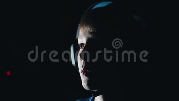 一个孩子的特写一个男孩在玩电子游戏的脸黑暗的房间视频的预览图