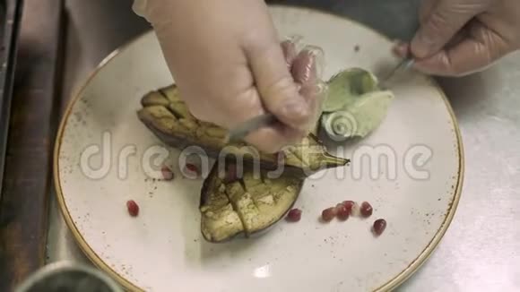 特写男厨用茄子装饰盘子的手持镜头视频的预览图