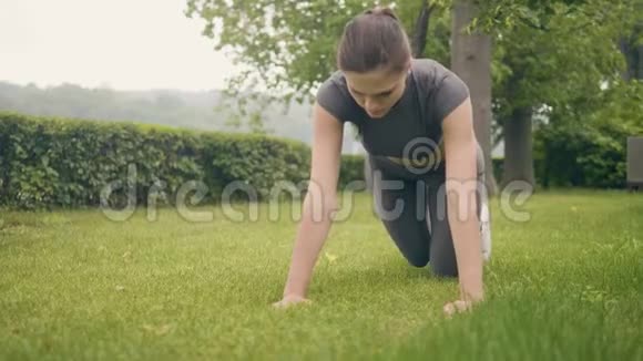 运动女子夏季公园草地上的俯卧撑练习视频的预览图