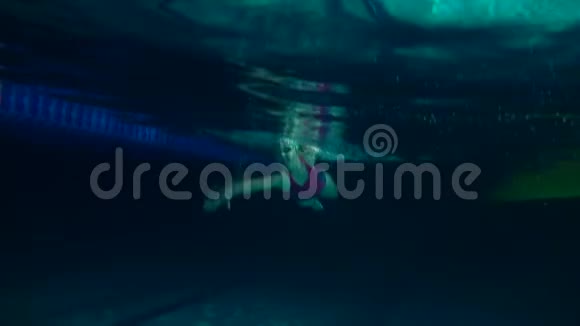 鳄鱼游泳运动员在游泳池里练习女游泳运动员练习翻转水下视野夜间射击视频的预览图