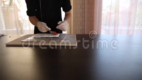 男寿司厨师把红鱼子酱托比克放在米饭和诺里上寿司制作工艺视频的预览图