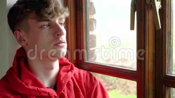 悲伤沮丧的少年男性少年一个坐在窗外看的成年男子视频的预览图