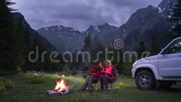 在山谷露营时一对夫妇在篝火旁聊天日落视频的预览图