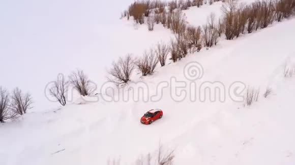 橙色的汽车正沿着一条冬天下雪的乡村道路行驶从无人驾驶飞机上俯瞰视频的预览图