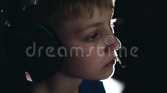 一个男孩在黑暗的房间里玩电子游戏的酷大镜头孩子们脸上的情绪视频的预览图