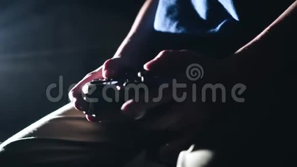 儿童用控制器手的特写这个男孩玩电子游戏黑暗的房间视频的预览图