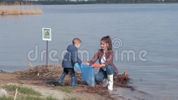 环境问题的解决方案男孩帮助妇女志愿者积极分子从塑料垃圾清理肮脏的河滨视频的预览图