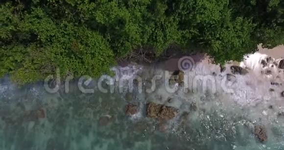 美丽的海滩上面有大石头蓝色的水和绿色的树空中拍摄4k视频的预览图