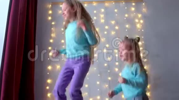两个女孩姐妹在家里跳着床在的内部有花环视频的预览图